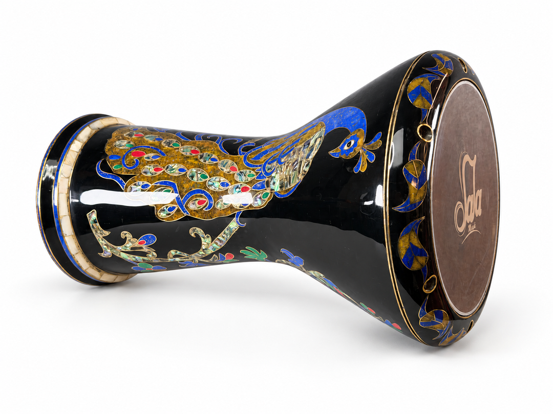 Sala Midnight Peacock Sombaty darbuka on its side, showing the Sala-branded drumhead and a blue-and-gold peacock with colorful tail details on a dark finish.